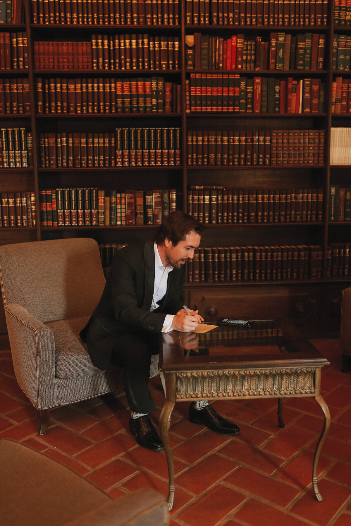 groom writing his vows in beautiful library