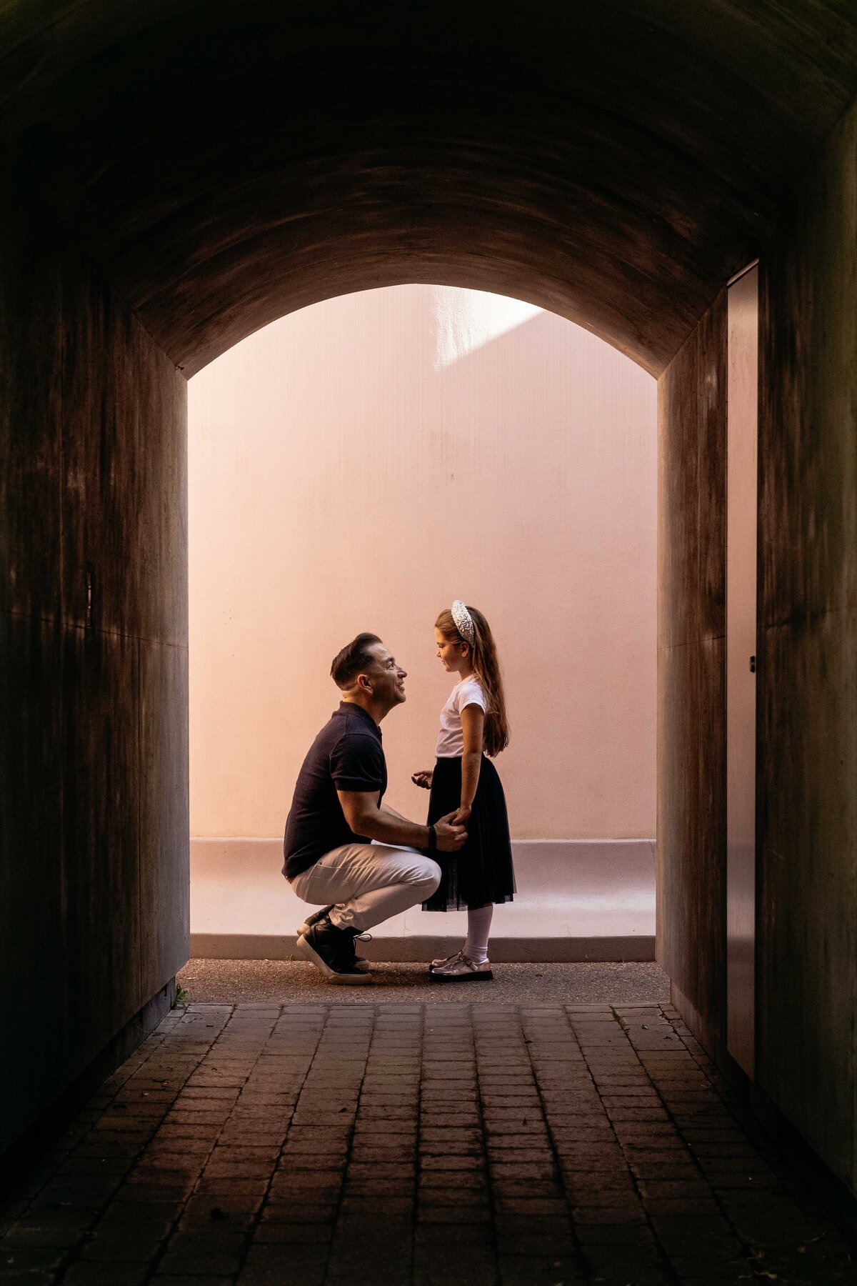Dad kneeling down to young daughter's height and looking into her eyes.