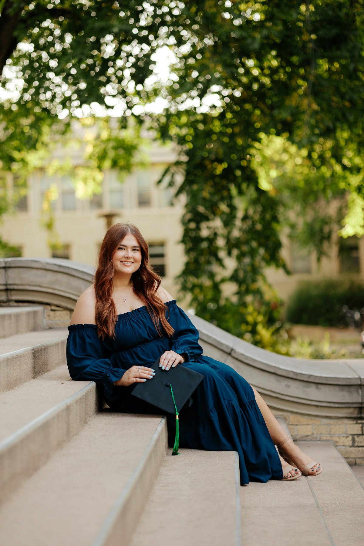 A Colorado State University graduate poses on the steps of the iconic Administration Building in Fort Collins during her senior grad session.