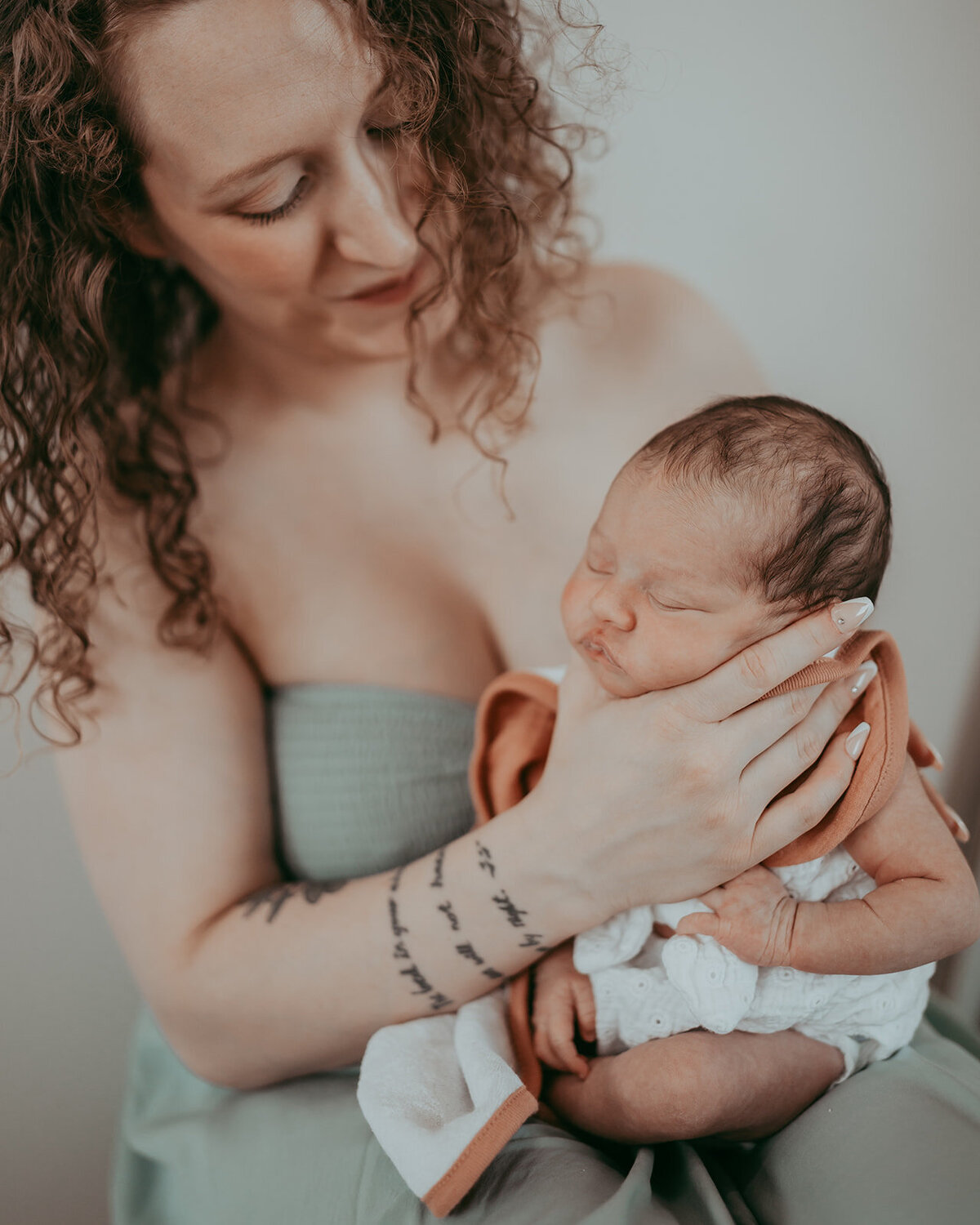 tattooed mom holds her newborn baby's face