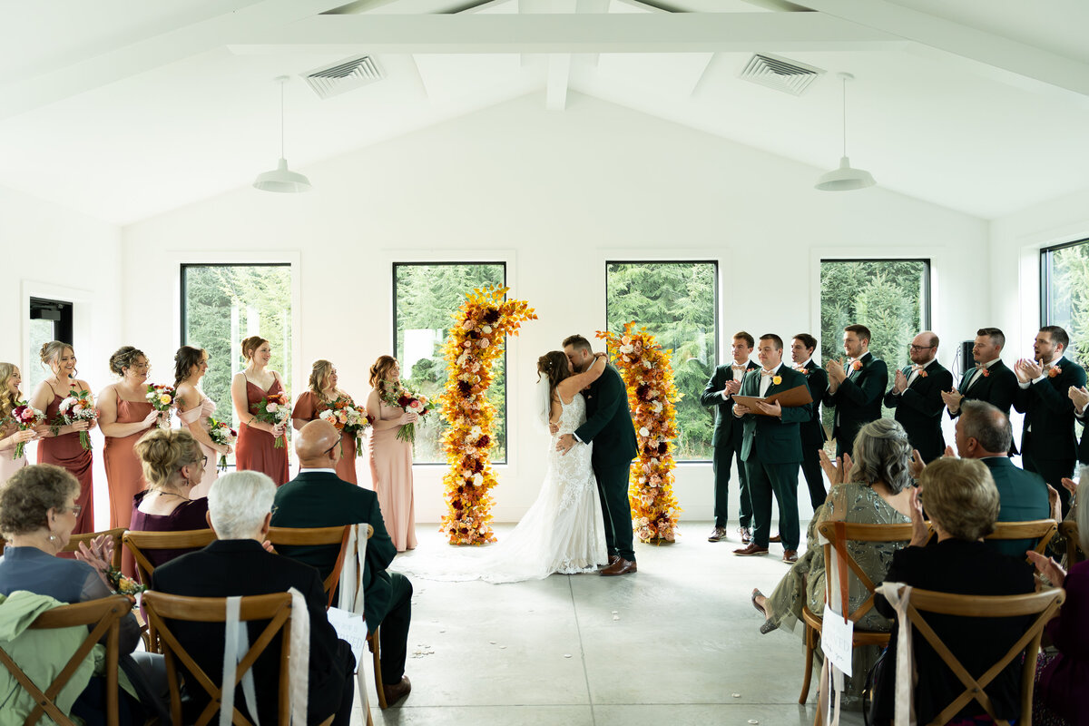 wedding first kiss at altar with flower arches at The Wellspring