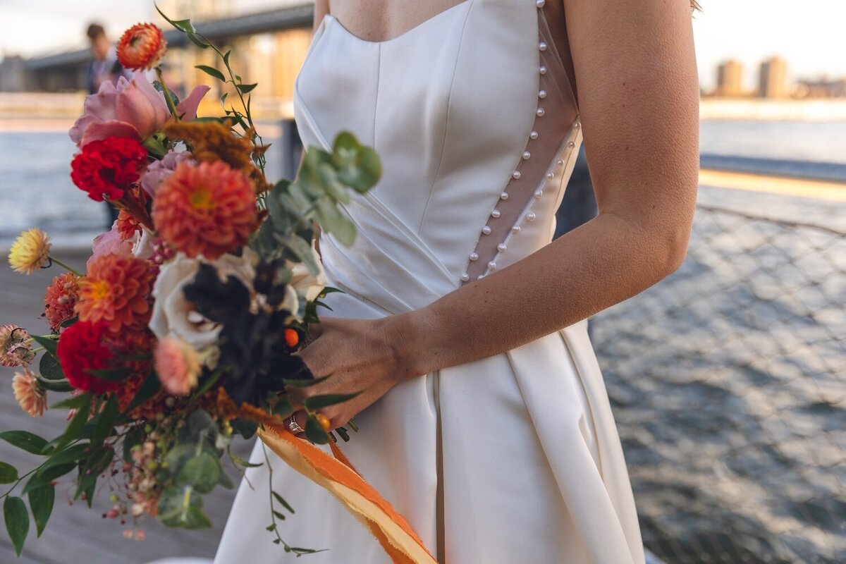 Bride holding colorful bouquet by the Brooklyn waterfront
