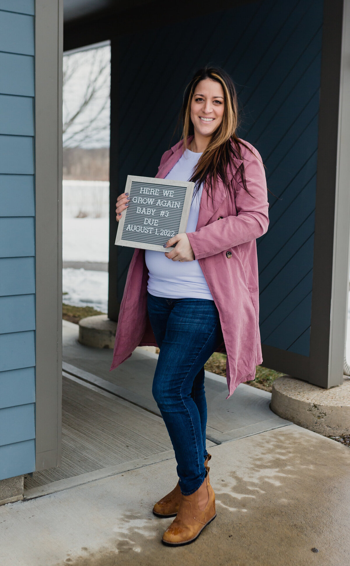 Pregnancy announcement with soon to be mom outside holding announcement board.n