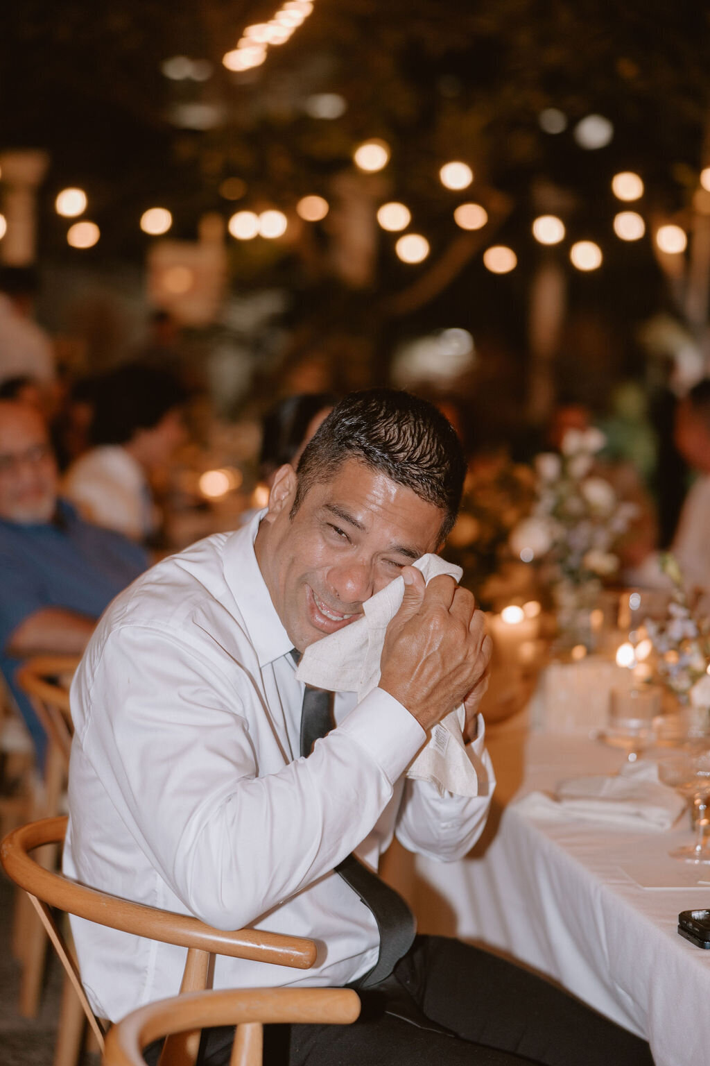 Man crying wiping tears at wedding reception