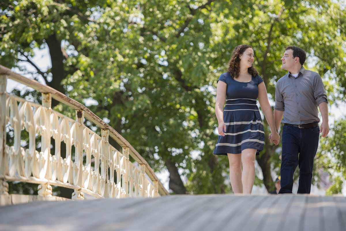 A couple holding hands and walking over a bridge together 