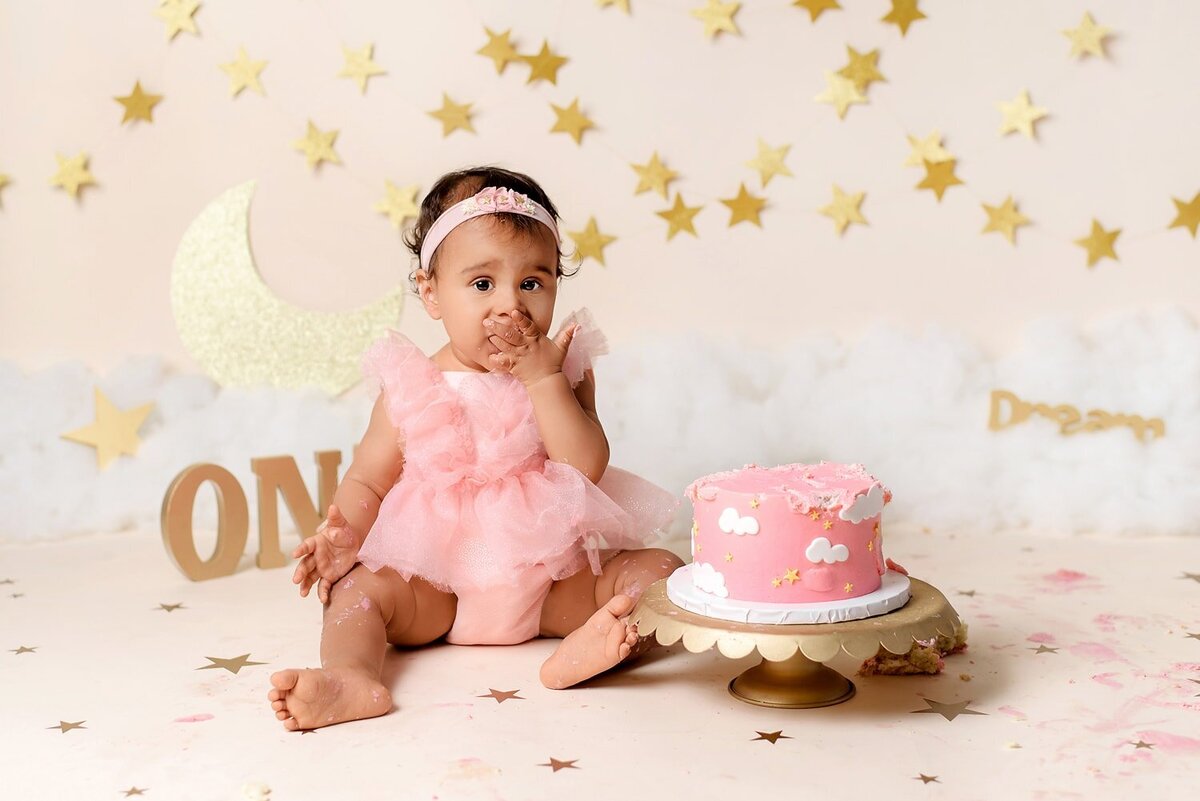 Cloud and star dream cake smash with 1 year old girl in pink romper.