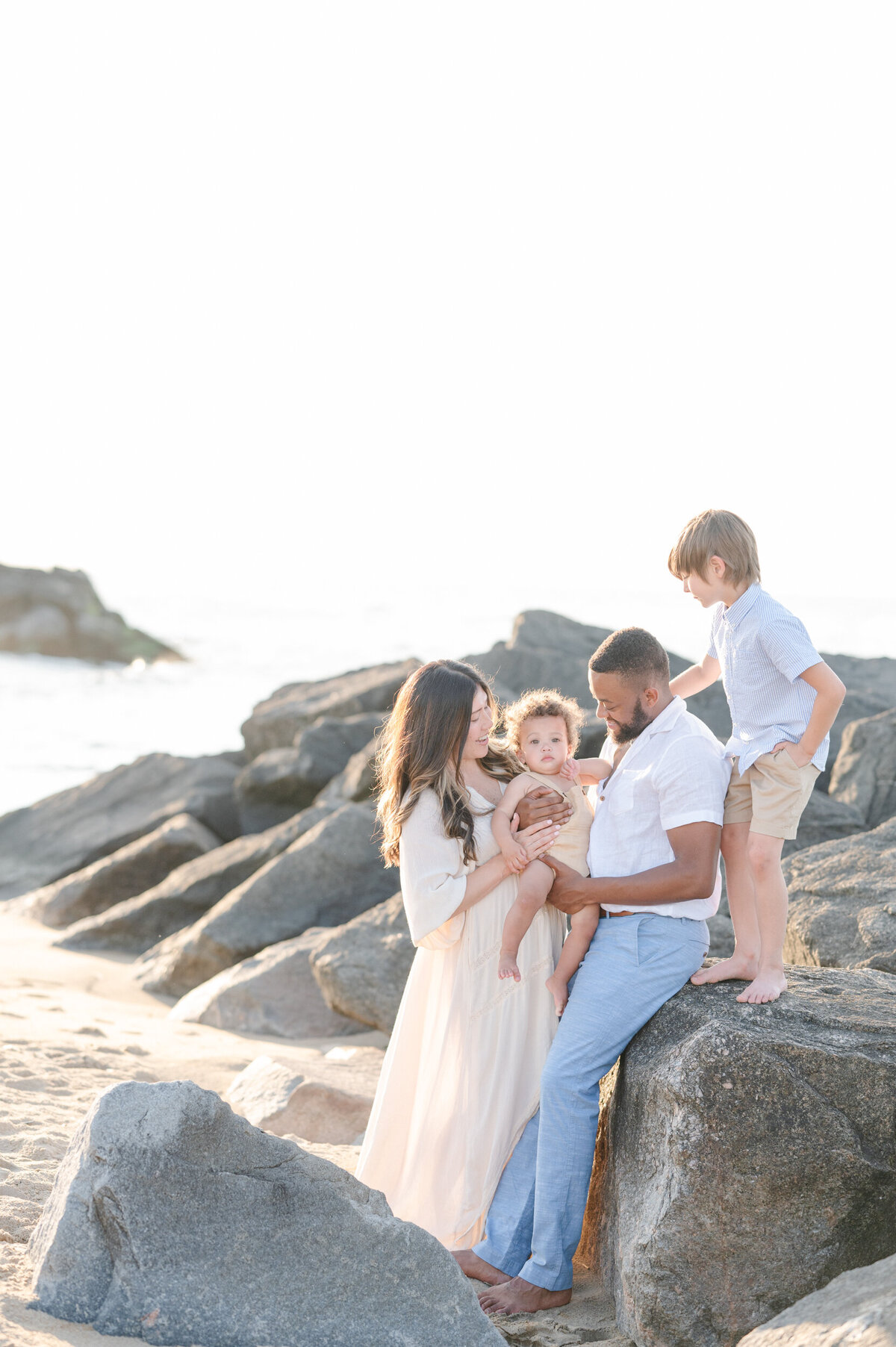 family-sitting-on-rocks-at-the-beach