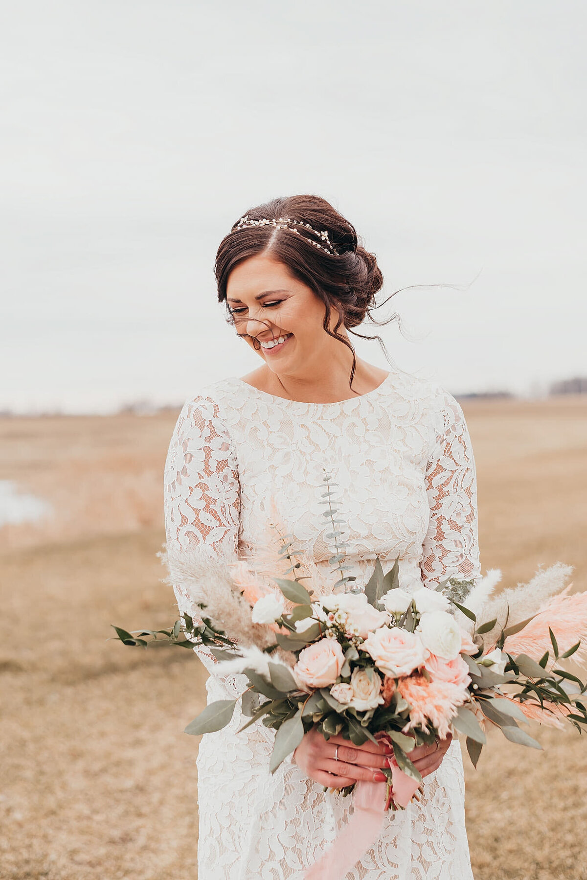bride smiling with her bouquet in a field