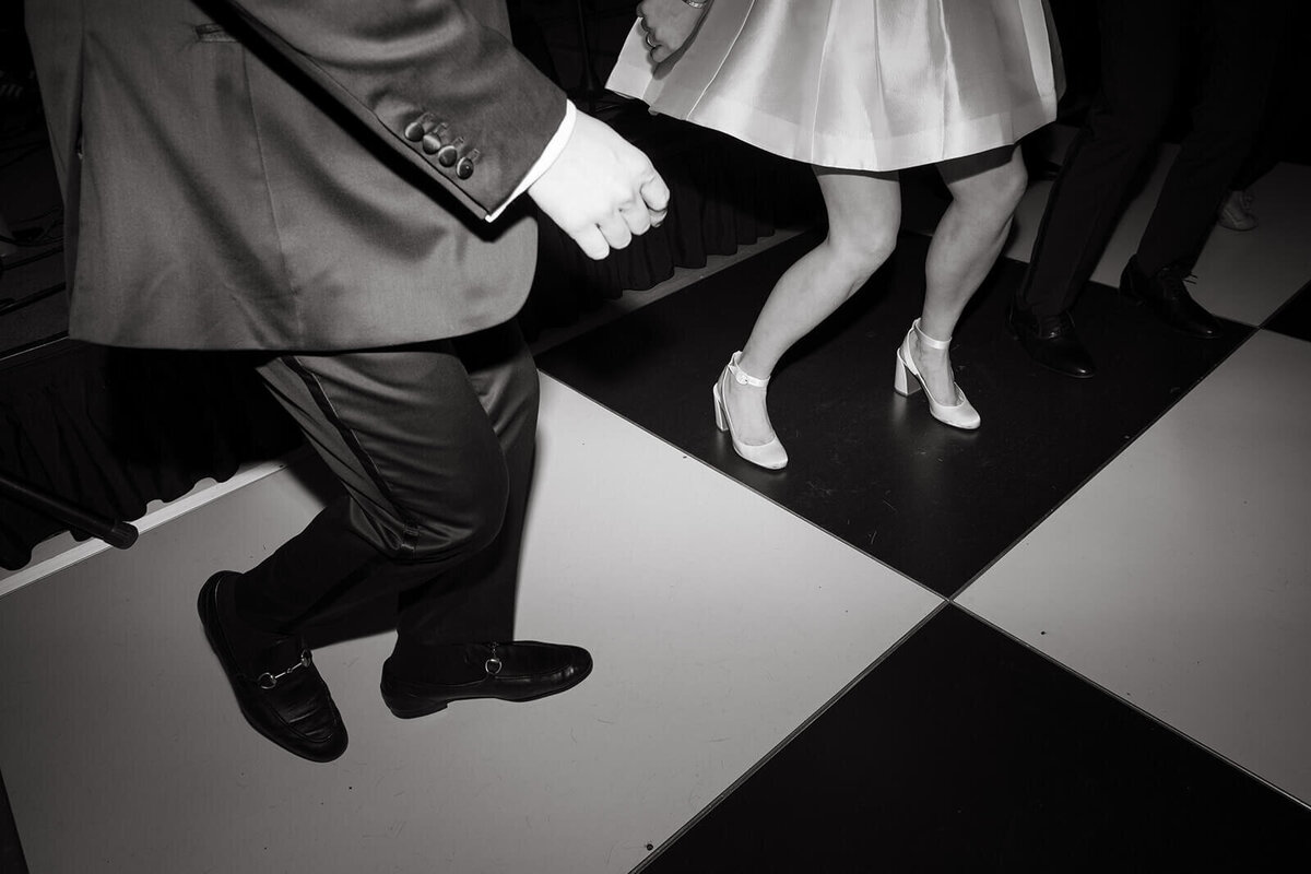 Black-and-white photo of the bride and groom's first dance at St. Regis Aspen, focusing on their feet moving on the dance floor.