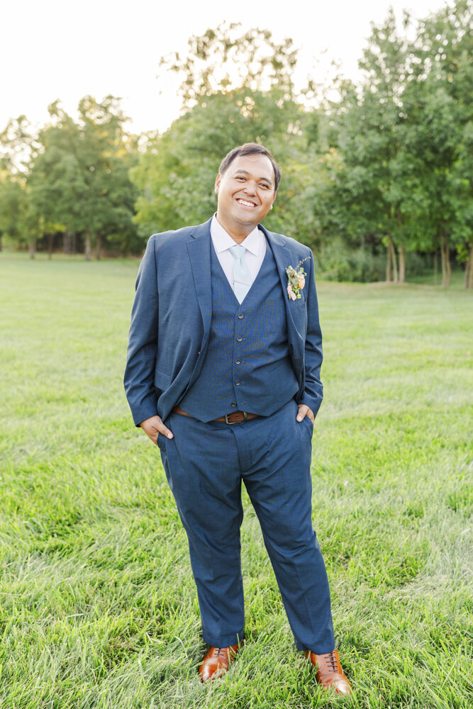 groom smiling in a suit with his hands in his pockets