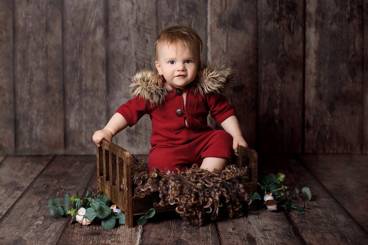 12 month old boy in red romper for first birthday photoshoot