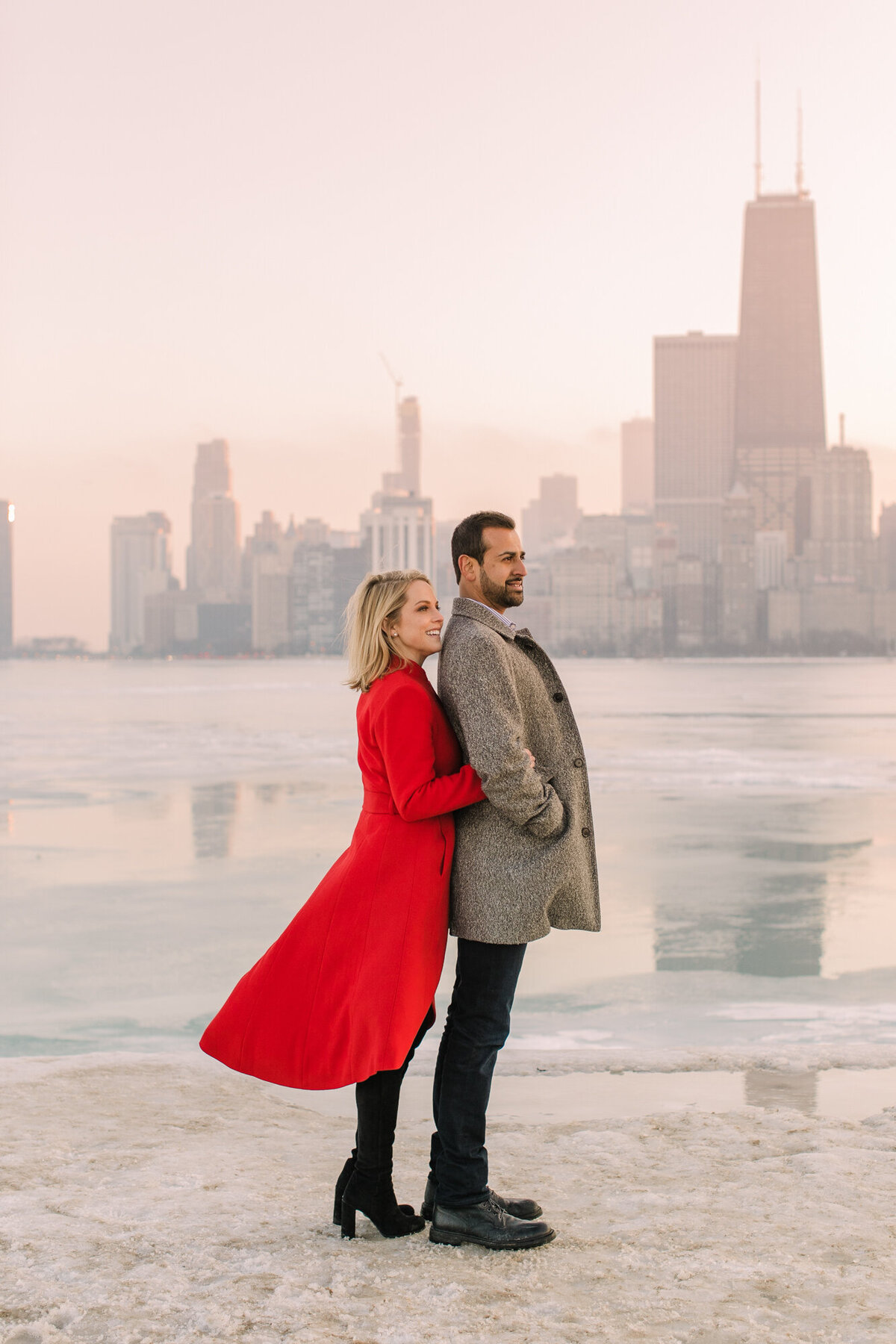 An engagement photo in front of a frozen Lake Michigan with the Chicago skyline in the background.