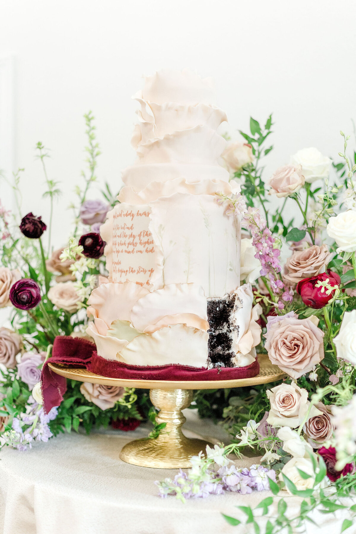 A beautifully designed luxury wedding cake surrounded by fresh floral arrangements, perfect for elegant celebrations at Willow and Stone Events near Charlotte, NC.