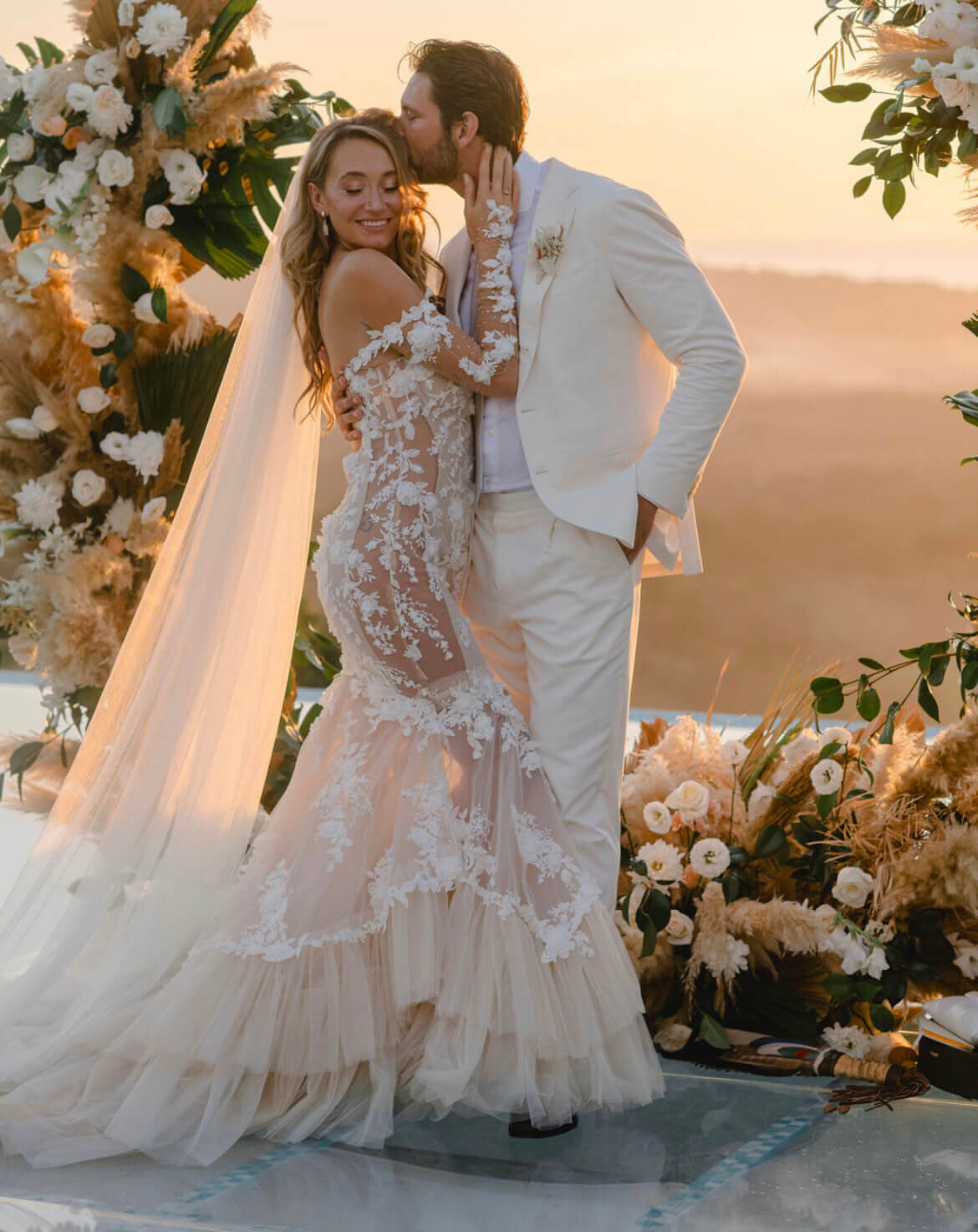 Bride and groom embrace at golden hour with flawless hair and makeup by mobile bridal beauty team for a tropical destination wedding