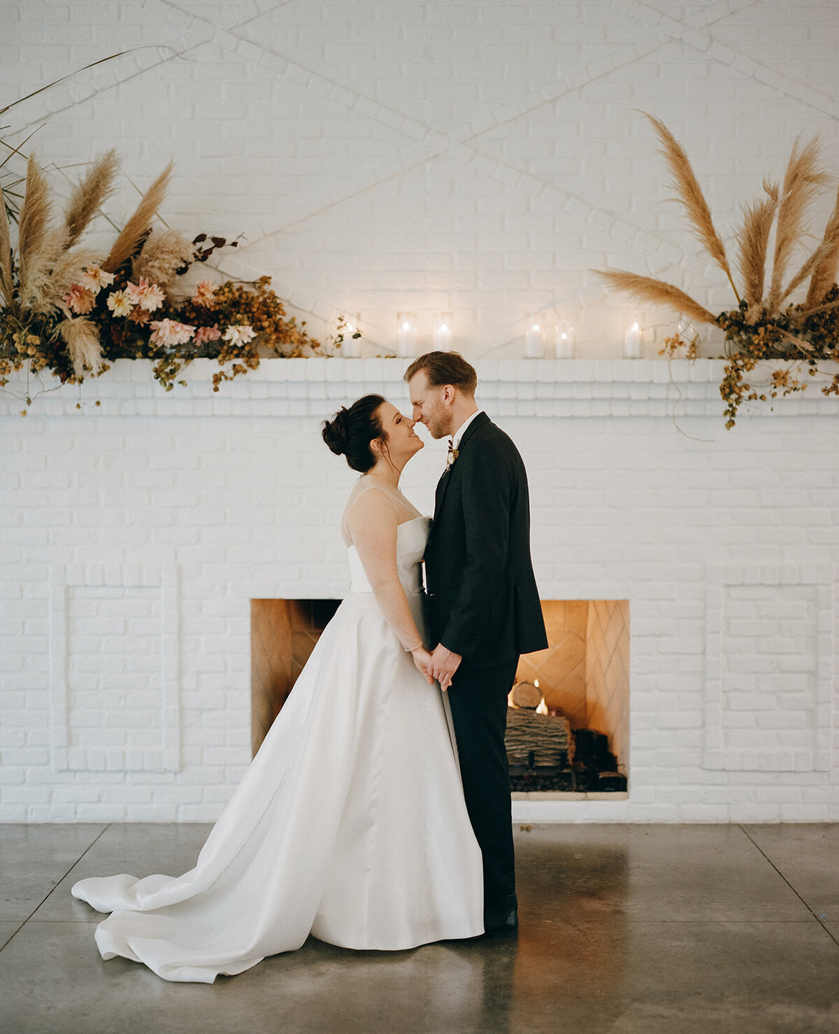 Bride and groom standing in front of the fireplace at a wedding at the Hutton House in Medicine Lake Minnesota