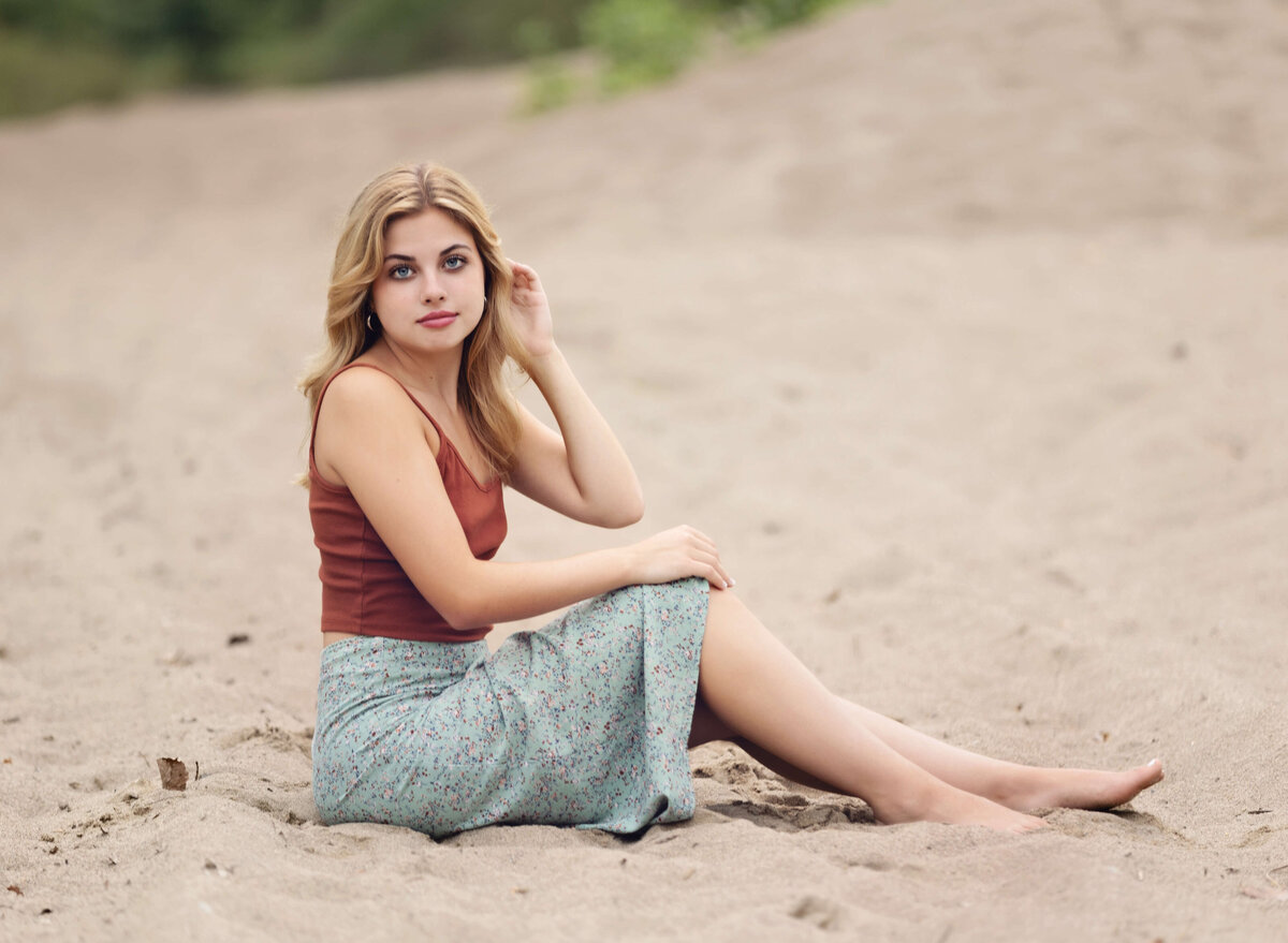 Photo of a senior girl sitting in the sand at Presque Isle State Park in Erie Pa