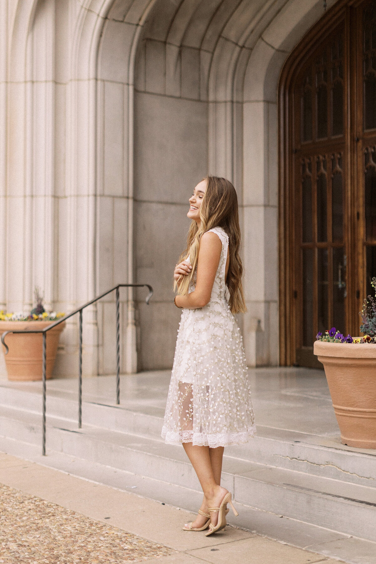 young woman with long hair laughs in front of historic library