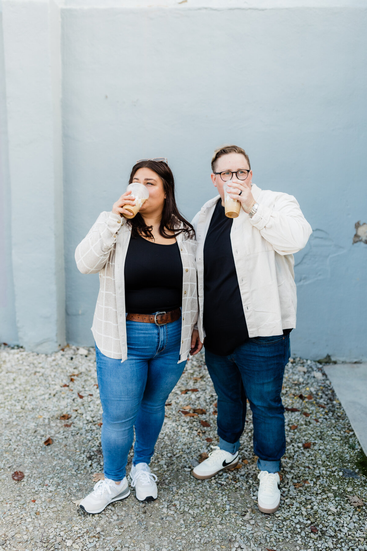 Couple sipping coffee and smiling while posing outside a café during their South Bend engagement session.