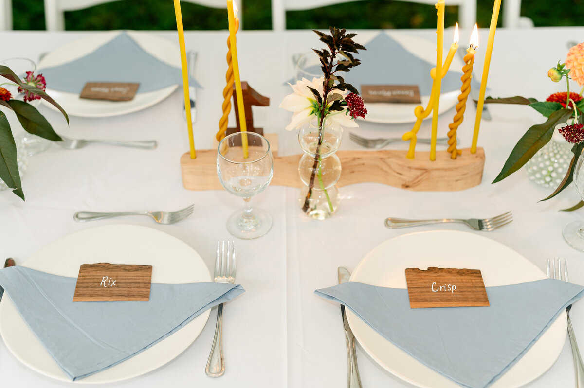 Wedding tablescape with blue napkins and yellow wavy candles