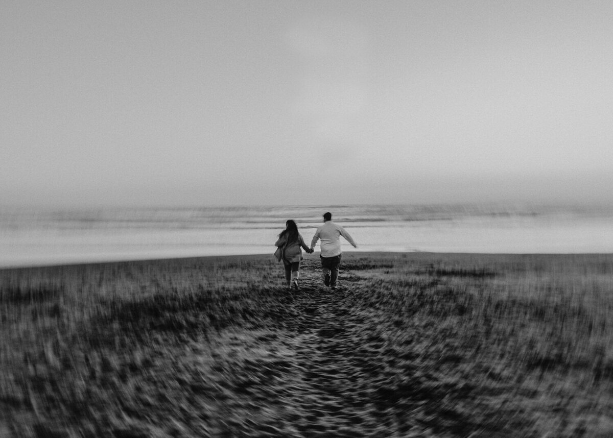 couple running towards the lake while holding each other's  hand