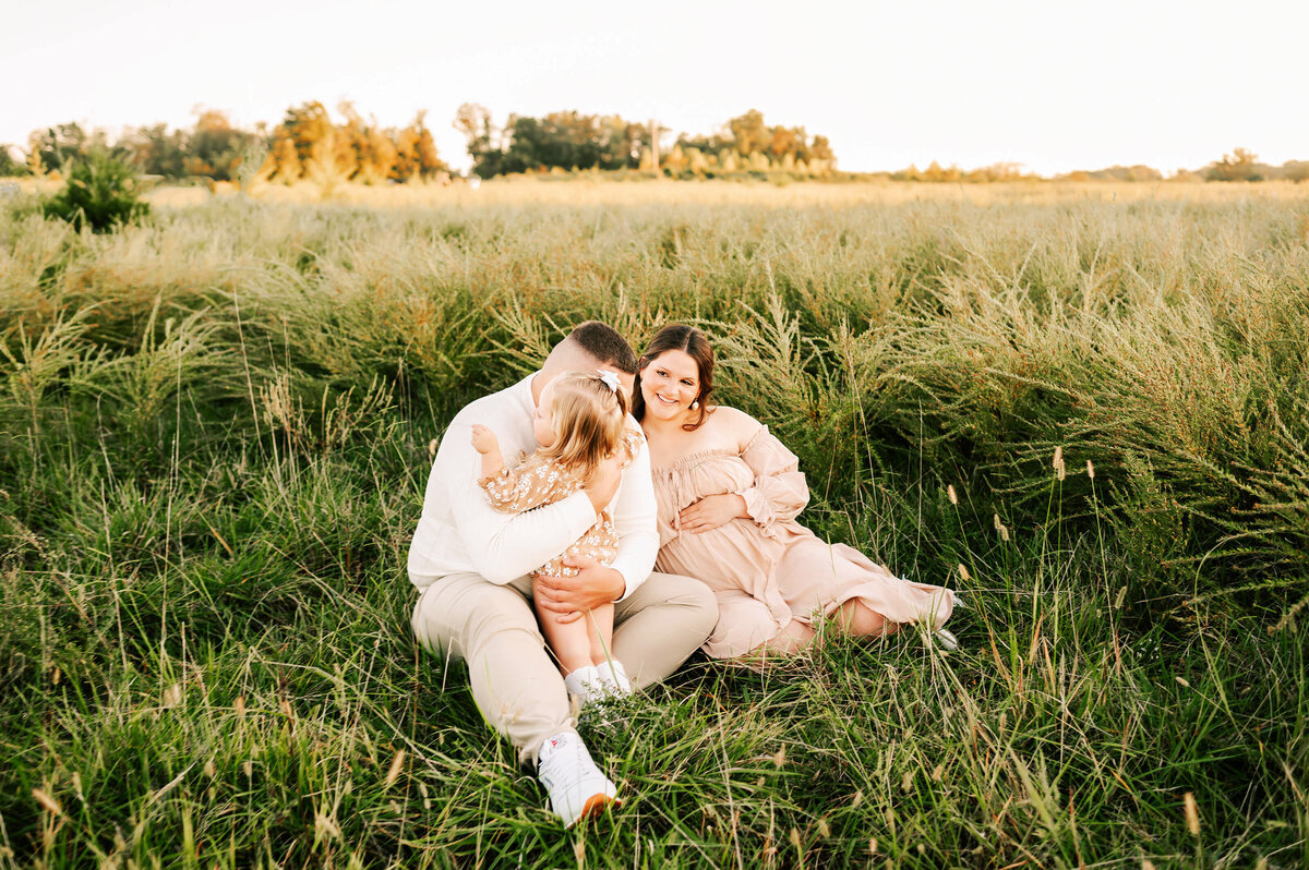 maternity photo of family hugging in field during Joplin MO maternity photography session