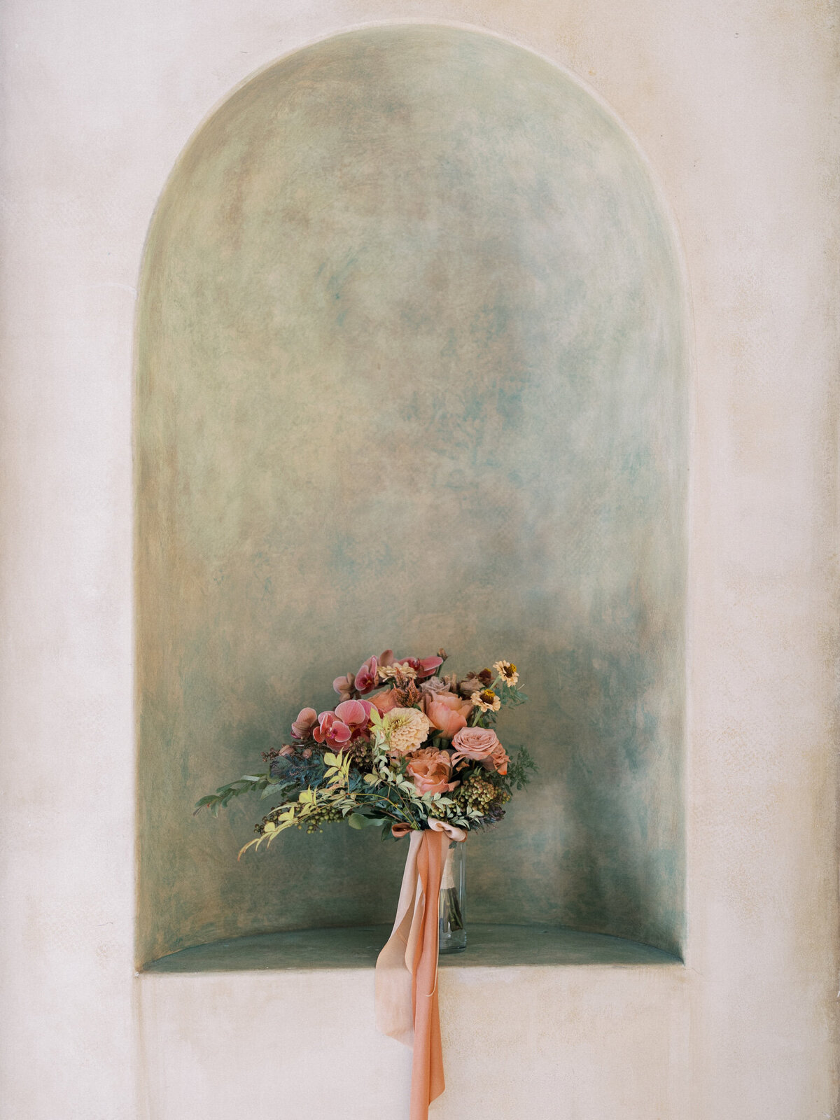 Romantic bridal bouquet styled against a Tuscan-inspired alcove—textural, timeless, and artfully composed.