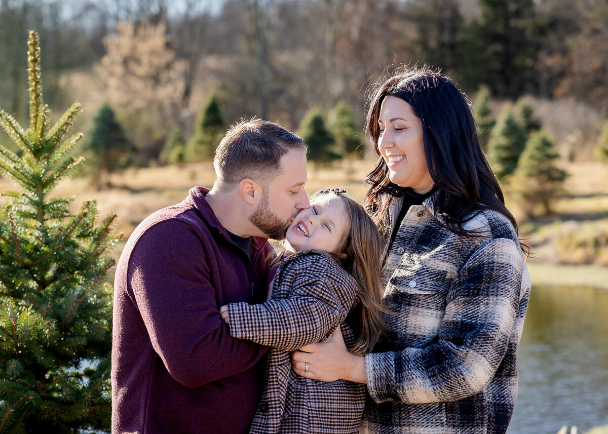 Family laughing and kissing at a Christmas tree farm in NJ