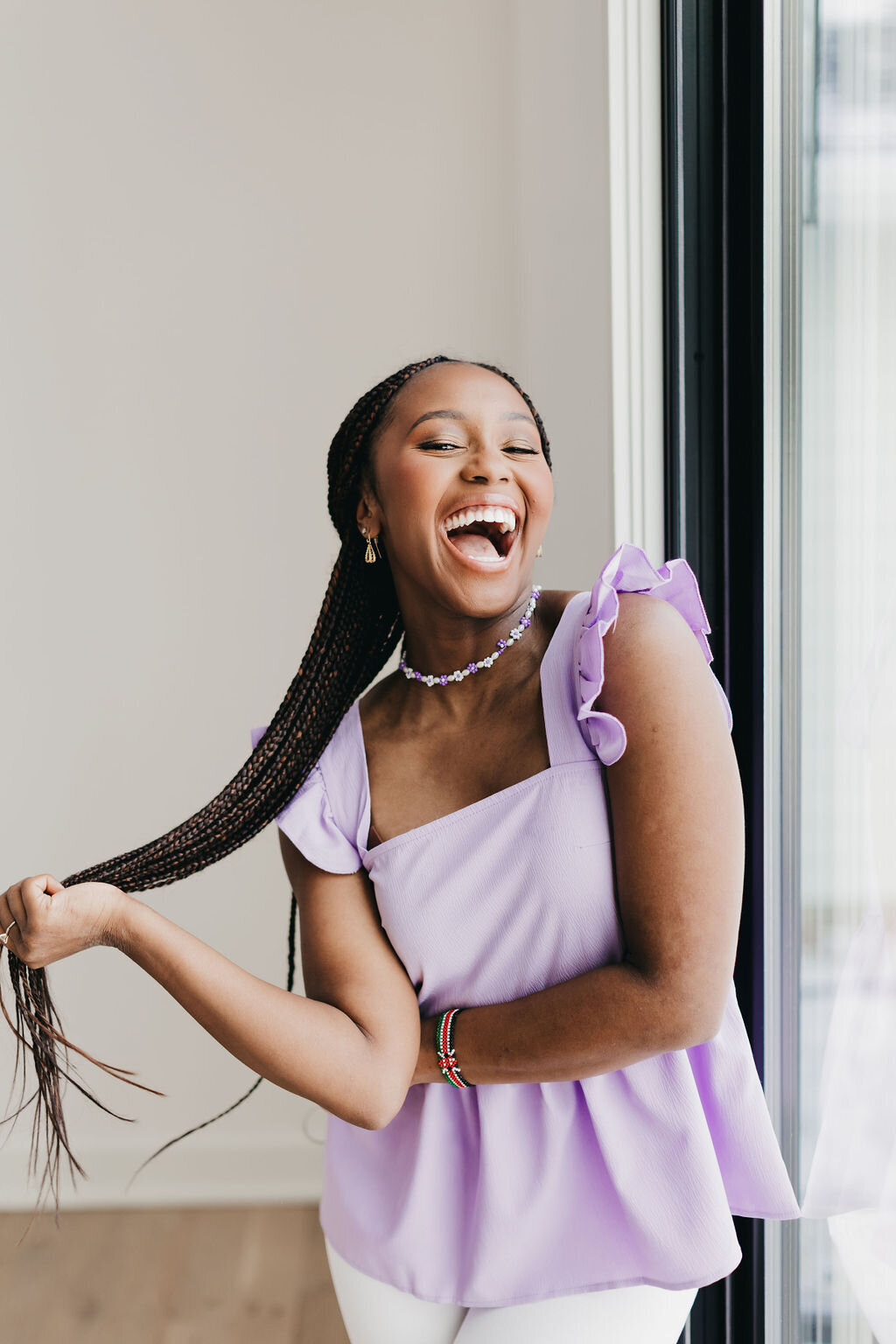 Juma Waganda in a purple top smiling and throwing her hair over her shoulder