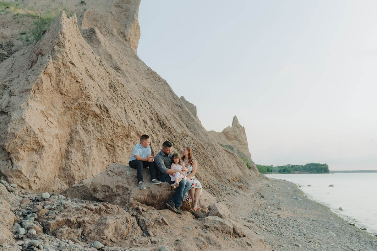 Family sitting on the rocks at family with two kids on the beach at family photo shoot in Finger Lakes, NY