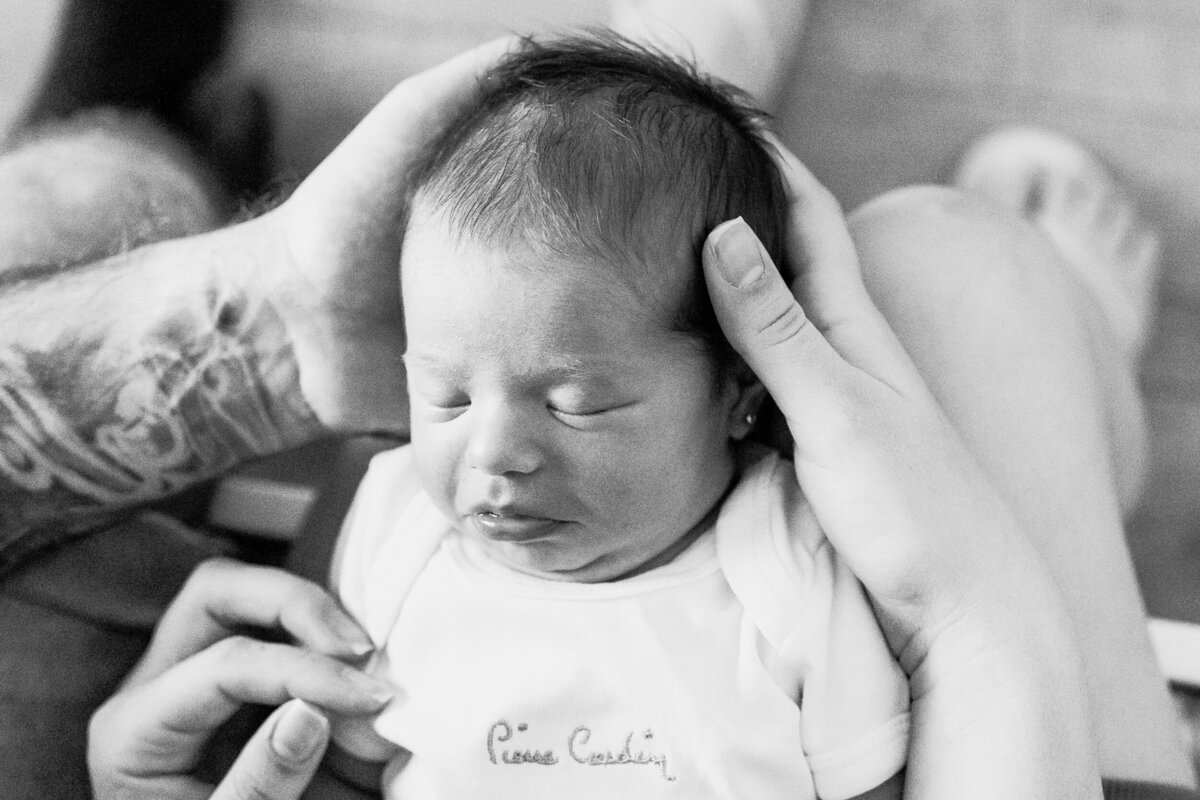 a baby is sleeping peacefully while head is sustained by her parents's embrace