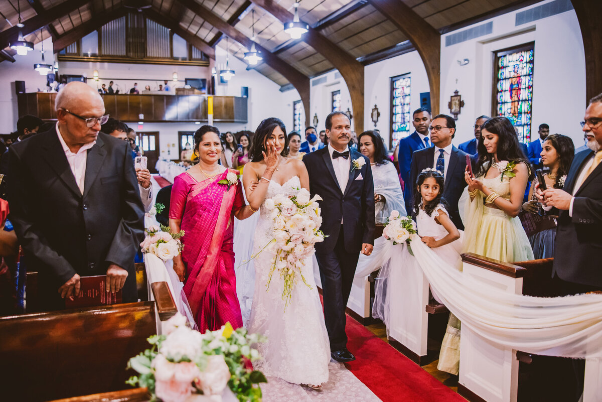 Indian christian bride crying tears during her processional church entrance having a first look with the groom during the wedding