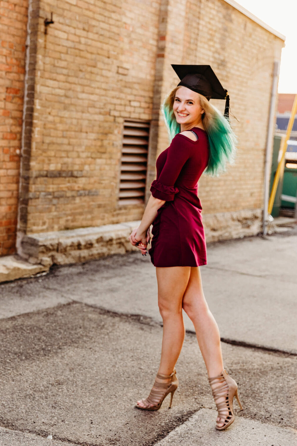 graduate posing in a dress and heels during session in Green Bay