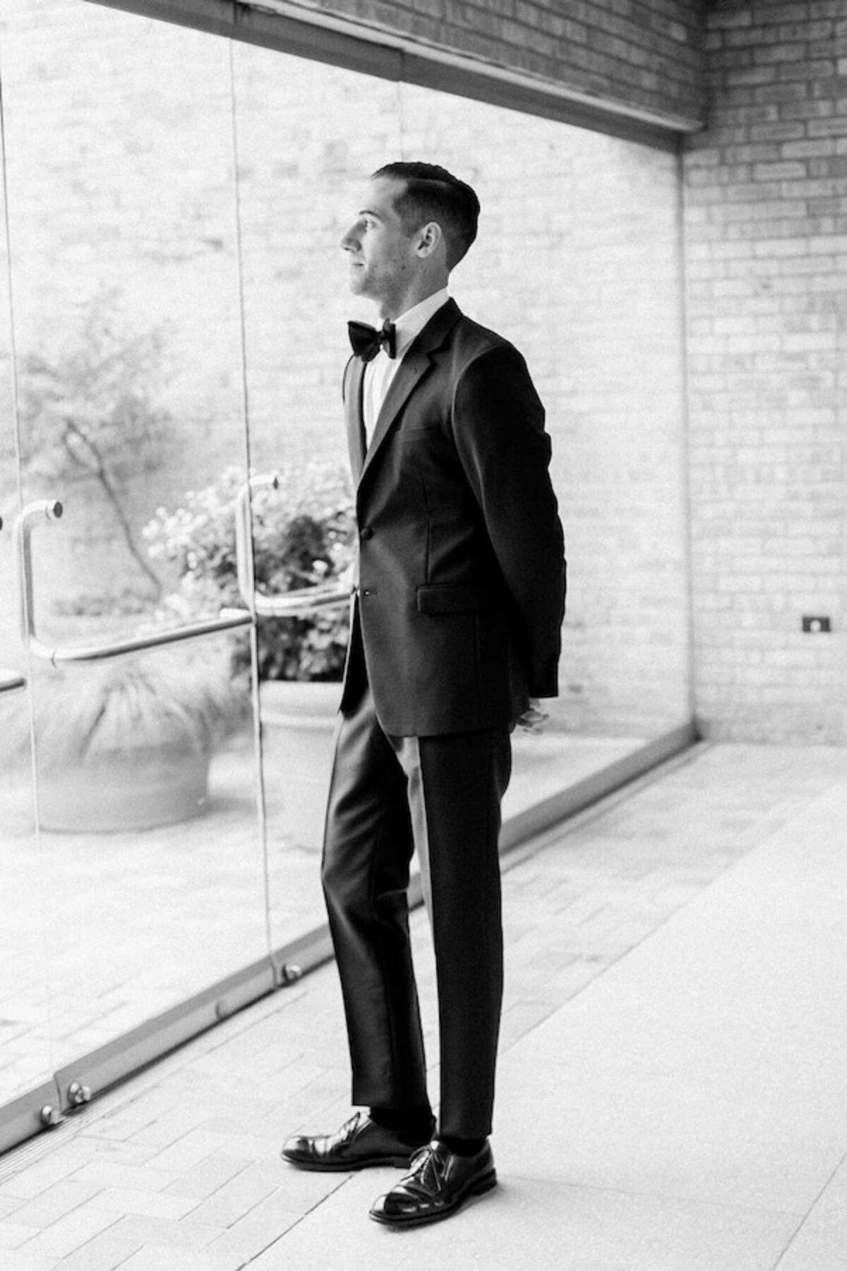 Classic and dapper groom in a tuxedo waits for the first look at a luxury Chicago outdoor garden wedding.