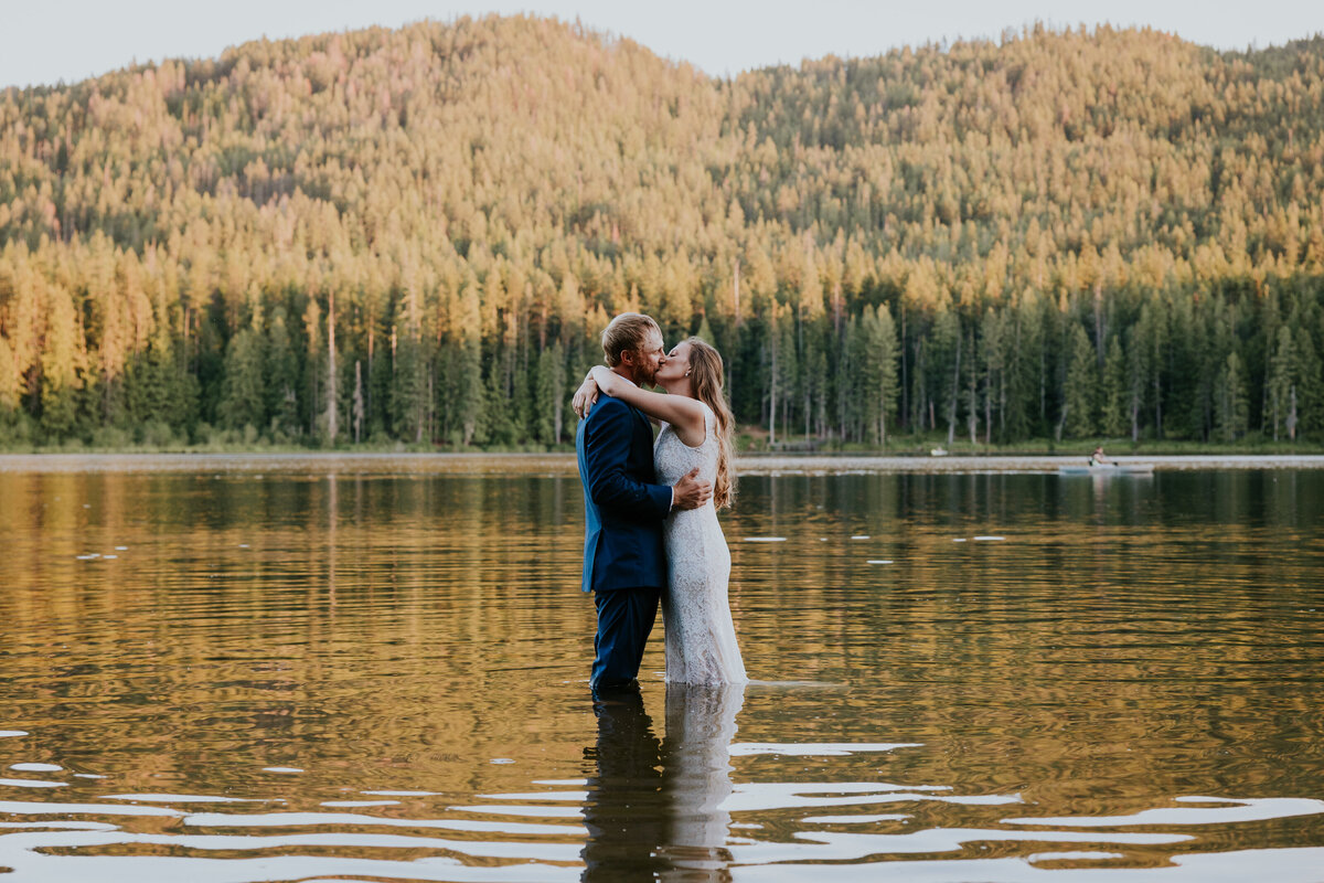 Bride and groom kiss will standing in Round lake, Idaho.