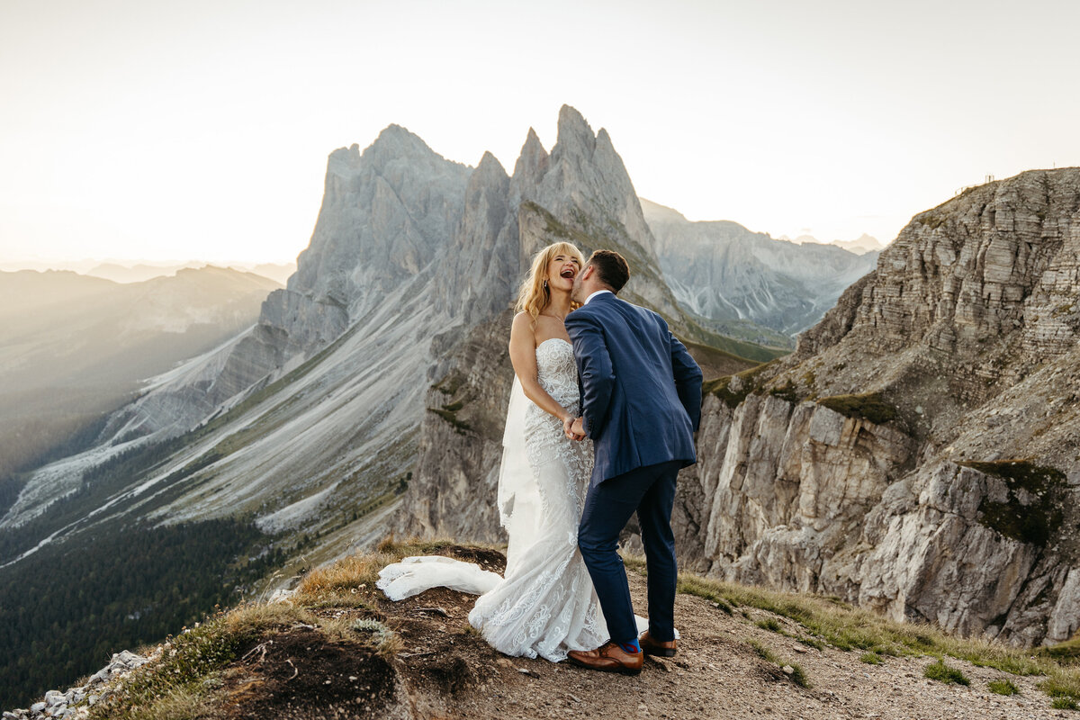Bride and groom standing on cliff edge overlooking the Dolomites