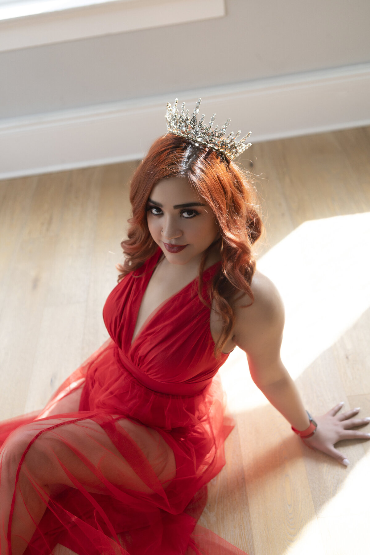 woman in red dress with a crown in a seductive pose on the floor