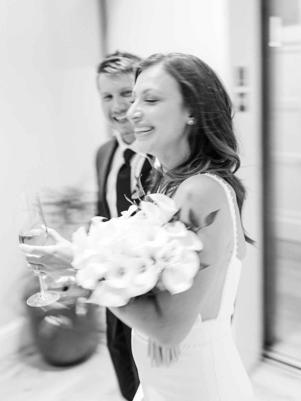 A joyful motion-blur shot of the bride and groom celebrating their Newport Beach wedding at Lido House with champagne and laughter