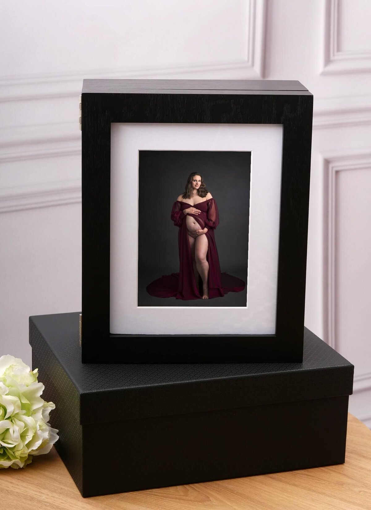 portrait of a pregnant woman in a black frame sitting on a side table
