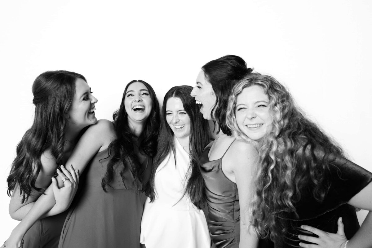 Group of women laughing together in a black and white portrait captured by Monochrome Portraits, a modern Phoenix photo booth experience.