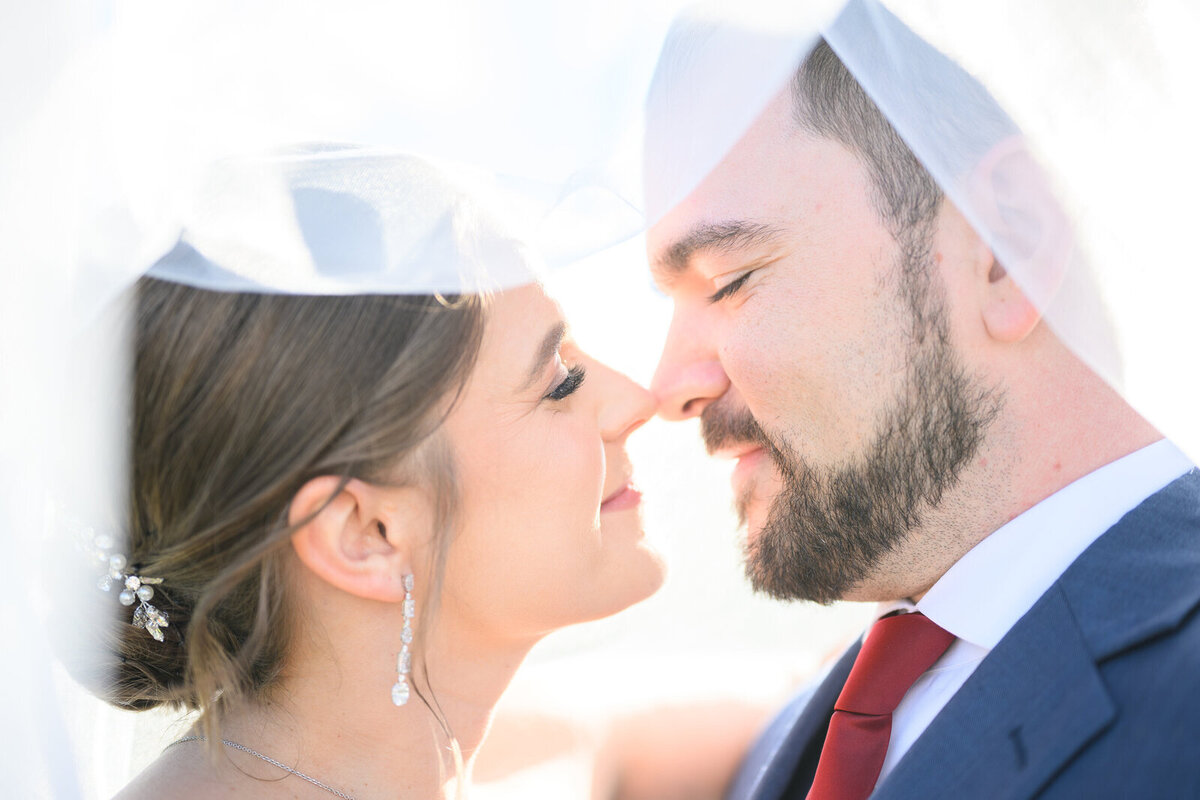 Bride and groom embrace under veil in close up shot