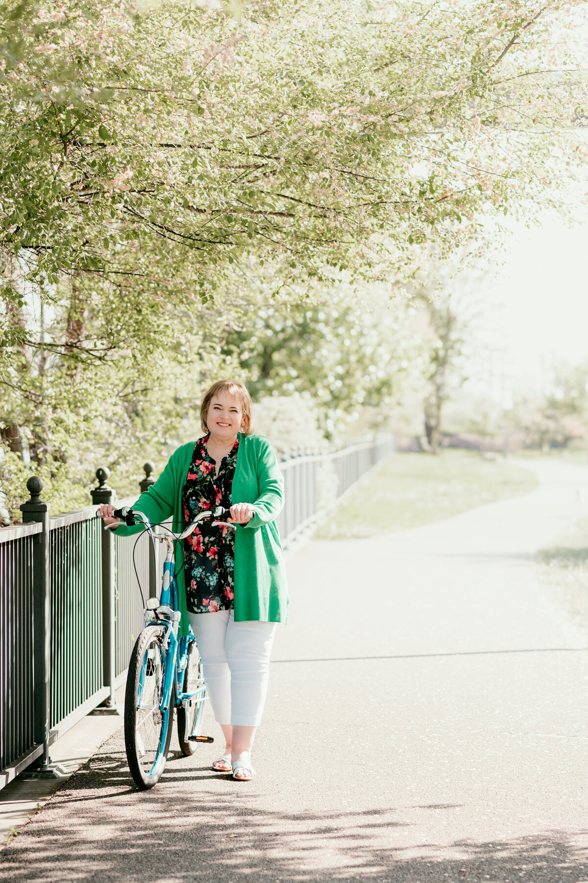 Active dating portrait of woman walking with bicycle along St. Paul riverfront trail near her apartment