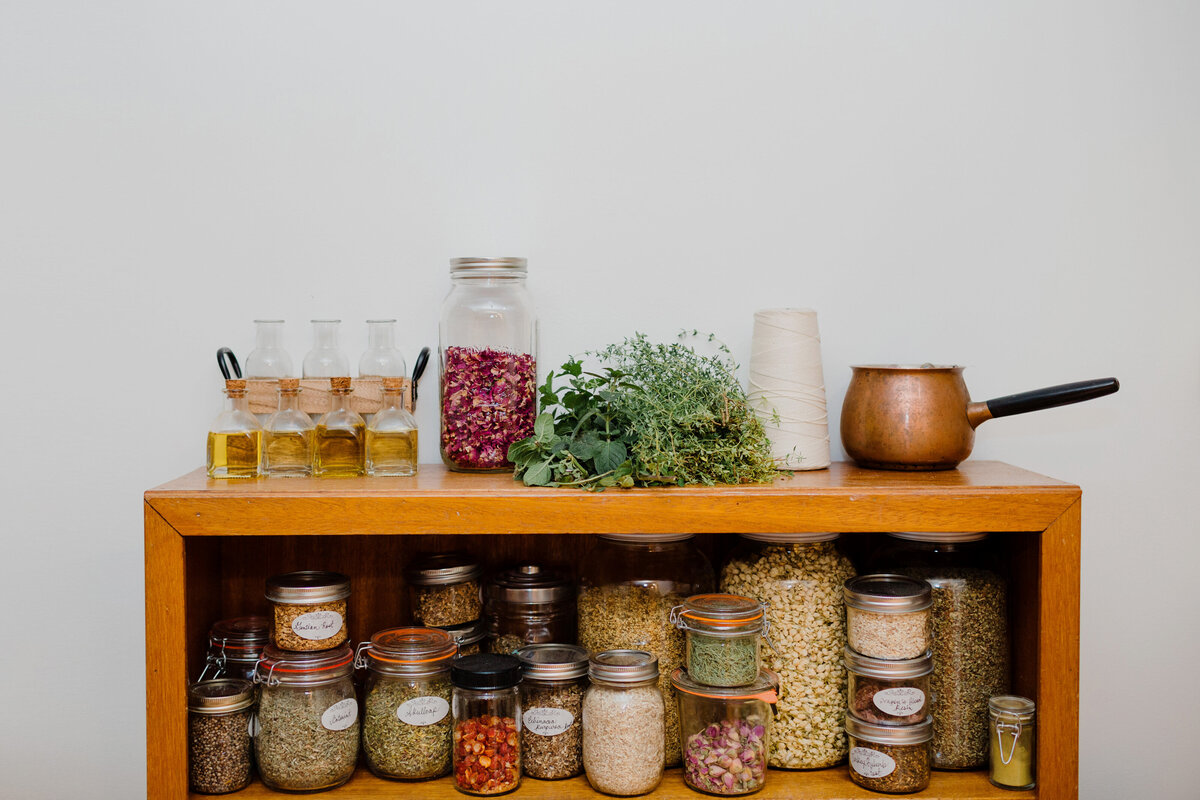 A shelf of dried herbs, flowers and clays