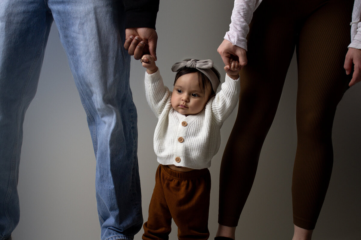 Minot parents hold the hands of their 3 month old daughter.