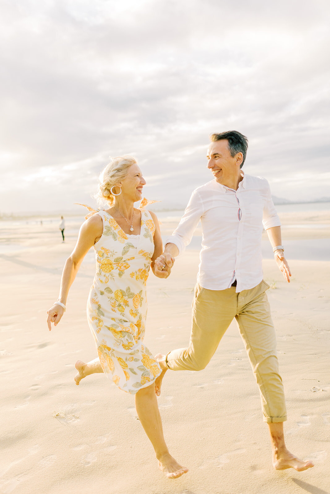 husband and wife running down the beach holding hands