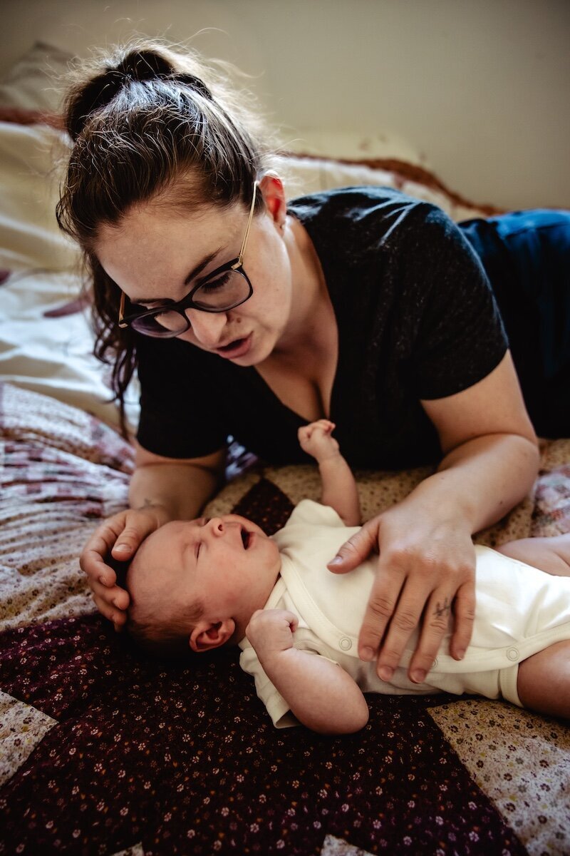 a newborn baby girl laying on a handmade quilt with her mom