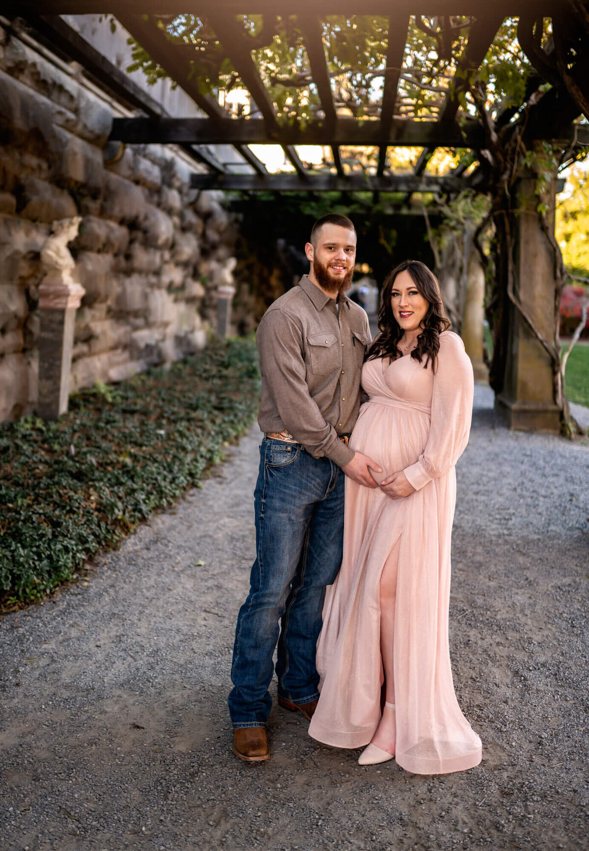 A young man and his expecting wife pose for a portrait at the Biltmore Estate during their session with an Asheville Maternity Photographer