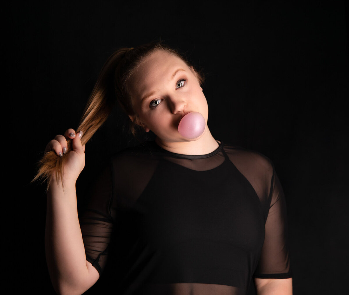 girl-blowing-bubble-in-all-black-studio-portrait