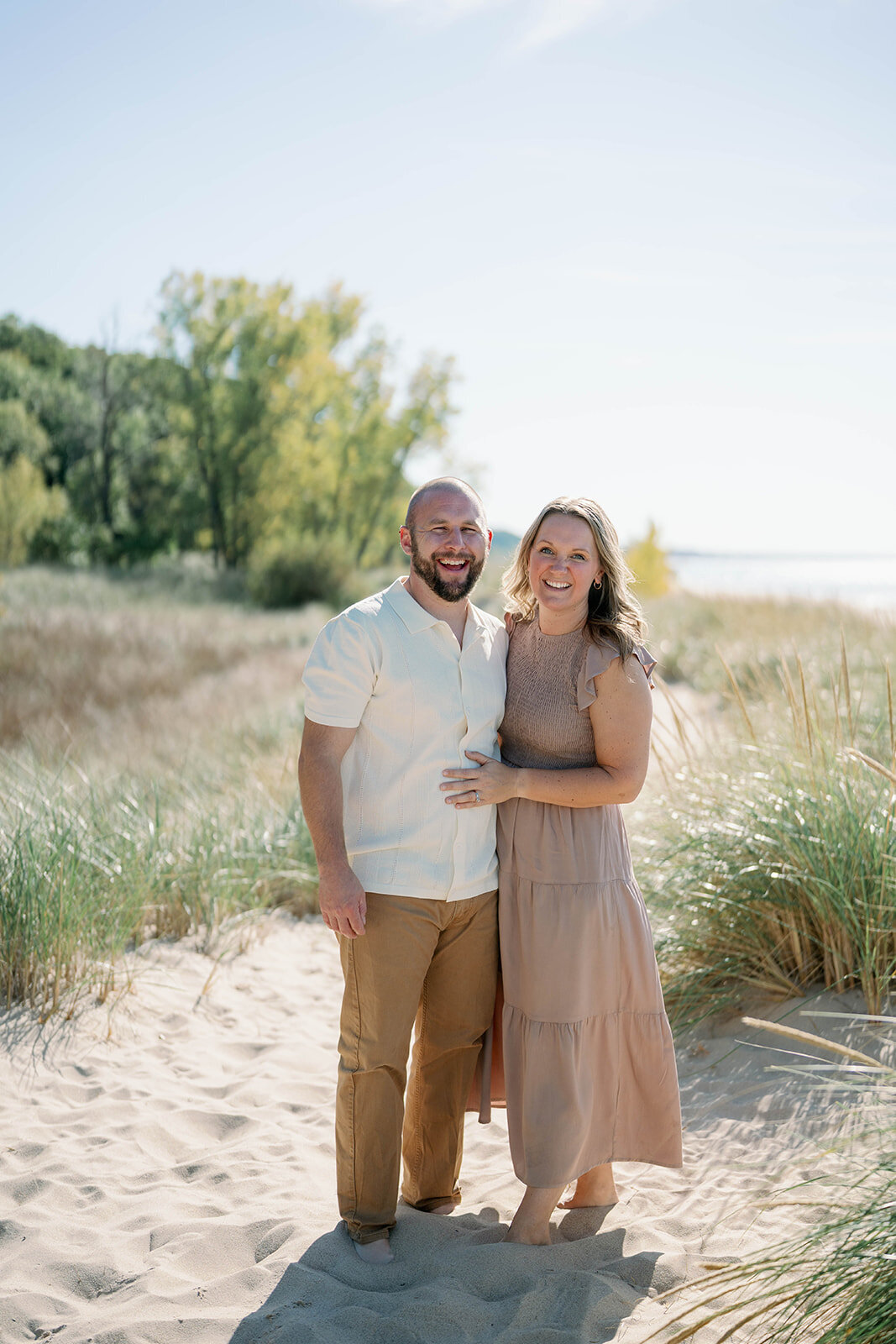A mom and dad standing together at Weko beach smiling 