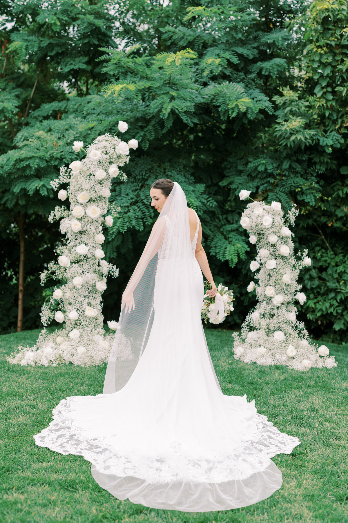 Bride standing in front of floral arch in gown