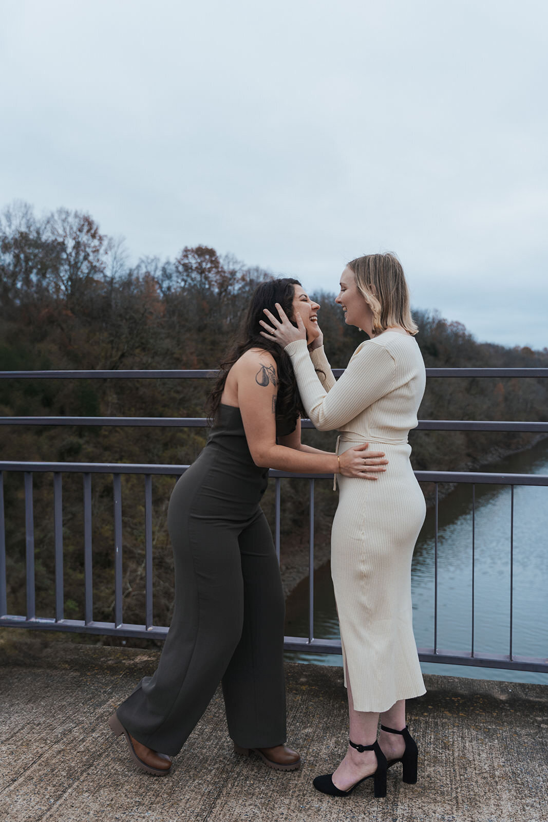 Wives hold each other's faces while smiling 